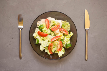 healthy salad, vegetable, tomatoes, cucumbers, iceberg, Cutlery, grey background. Top view. Copy space.