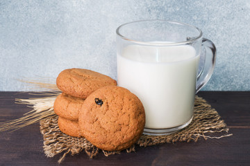 Natural oatmeal cookies and a glass of milk on a wooden background. Rustic style.