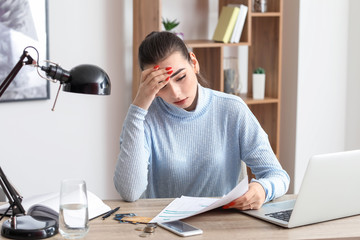 Fototapeta premium Worried young woman in debt at home