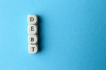 Cubes forming word DEBT on color background