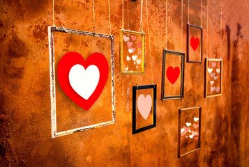 Hearts in old frames and hanging by the old orange wall background, Showing your Love and Valentines day concept