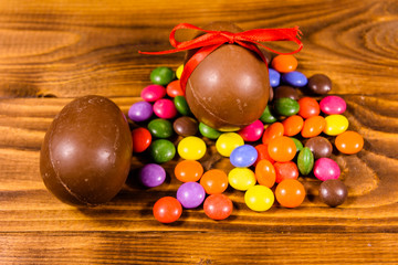 Chocolate easter eggs and multicolored candies on wooden table