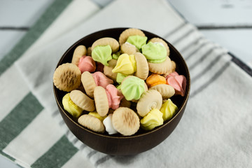 Sugar cookies on a wooden bowl isolated on colorful napkin background.