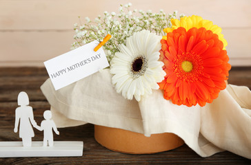 Beautiful flowers and paper with text HAPPY MOTHER'S DAY on table
