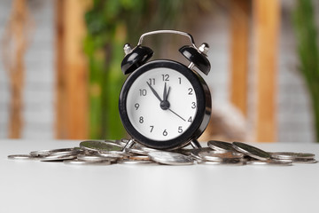 Alarm clock and money coins on the table.
