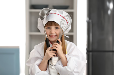 Cute little girl dressed as chef playing at home