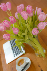 Arbeitsplatz Homeoffice Notebook Laptop auf Tisch Schreibtisch mit Blumen Tulpe und Tasse Kaffee