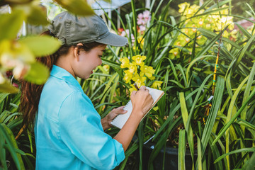Young women write note among orchid garden. Colorful orchids, Orchid flower bloom..