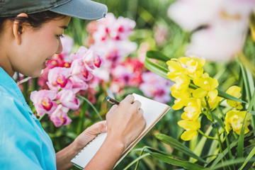 Young women write note among orchid garden. Colorful orchids, Orchid flower bloom..