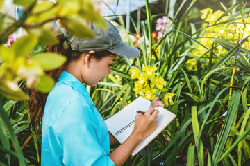 Young women write note among orchid garden. Colorful orchids, Orchid flower bloom..