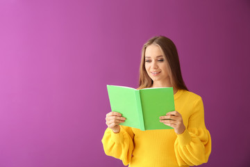 Beautiful young woman with book on color background