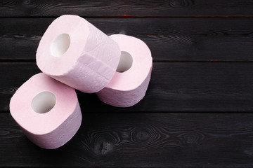 Pastel pink toilet paper rolls on black wooden background