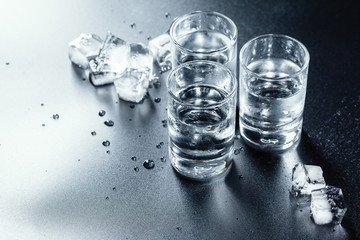 Cold vodka in shot glasses on a black background.