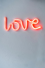 Red Neon Love Sign on a white wall. Selective focus.