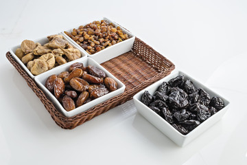 datteri prugne fichi uva passa ciotole con cesto fondo bianco