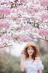 Beautiful asian young woman wearing hat outdoors in a forest. Pretty asian girl model  over blur flower background in garden.