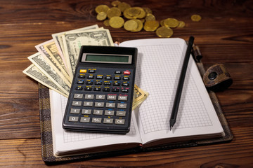 Notepad with dollars, pencil and calculator on wooden desk. Financial planning concept