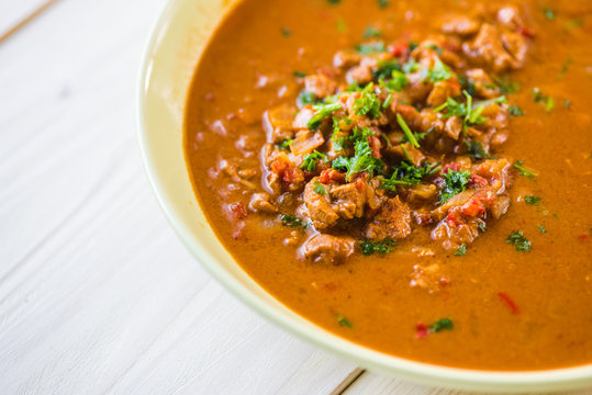 Rindfleischeintopf oder Gulaschsuppe mit Fleischst&uuml;cken in roter Tomaten sauce