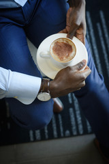 Fototapeta na wymiar Businessman with watch on his wrist holding mug with morning espresso coffee