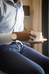 Businessman with watch on his wrist holding mug with morning espresso coffee