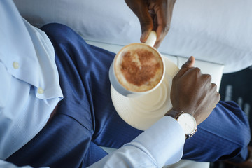 Businessman with watch on his wrist holding mug with morning espresso coffee