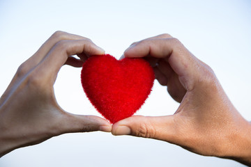 Red heart in woman and man hands, hands holding a soft heart shape, Couple love, Valentine's Day.