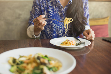 Spaghetti on a fork. Girl keeping fork with spaghetti.  Young woman eating Italian pasta.