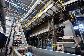 Wide angle view at recycling plant conveyor belt transports garbage inside drum filter or rotating cylindrical sieve with trommel - obrazy, fototapety, plakaty