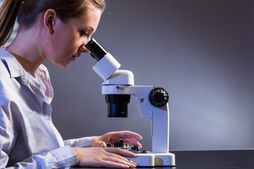 Young computer technician examining a printed circuit board. Microchip production factory.