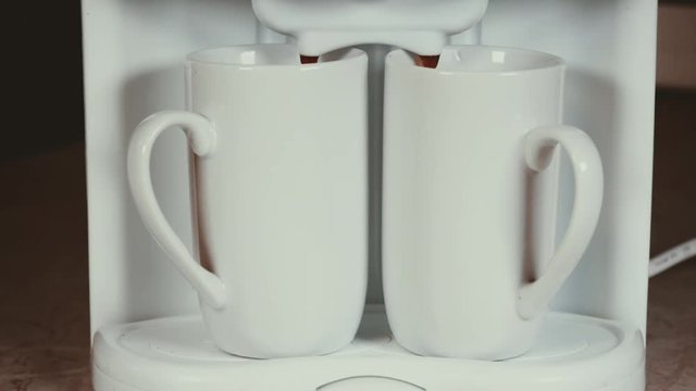 Closeup of automatic coffee machine or coffeemaker pouring espresso coffee in cups.