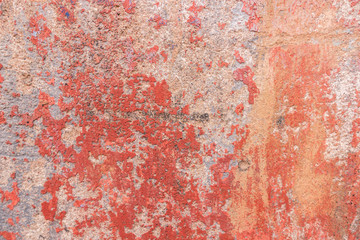 Old weathered painted wall background texture. Red dirty peeled plaster wall with falling off flakes of paint.