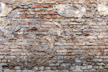 Old vintage dirty brick wall with peeling plaster texture background