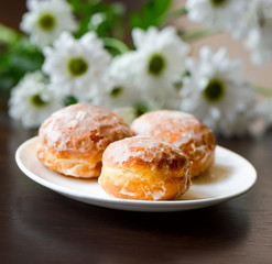 Obraz na płótnie Canvas Donuts on a white plate with flower on the table