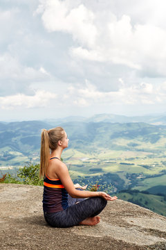 Yoga girl meditating on mountain over landscape