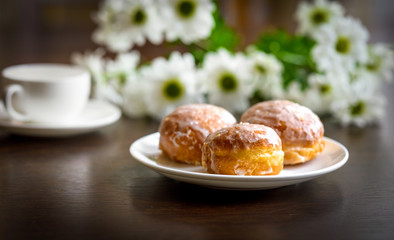 Donuts on a white plate with flower on the table