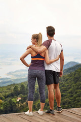 Sporty couple with arms around each other admiring view