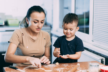 mom and son prepare dough from flour will bake bows