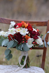 bright autumn wedding bridal bouquet, standing on a chair in the woods. floral arrangement of flowers to celebrate the holiday decor