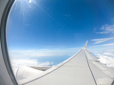 View from airplane window over airplane wing - Clouds and sky with sun reflection - aircraft, airship concept
