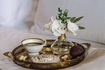 a tray of cookies and a cup of coffee next to a vase of flowers