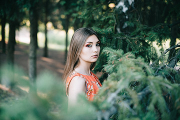 Beautiful young girl in a summer red dress in a park