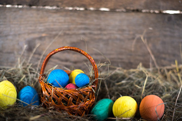 Easter eggs in a basket on a hay with a blurred background