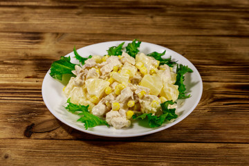 Festive salad with chicken breast, sweet corn, canned pineapple and mayonnaise on wooden table