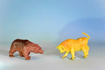 Toy Bear and Bull Figurines on Blue Background