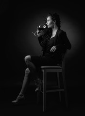 Obraz premium Portrait of attractive brunette with glass of wine on a black bacground.