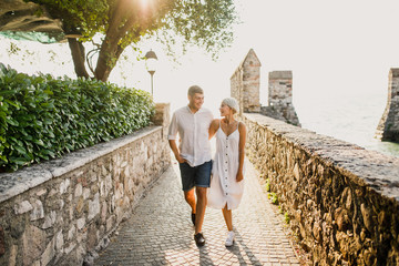 young beautiful couple girl in white dress man in white shirt walks at sunrise on the seashore