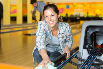 female employee cleaning bowling alley
