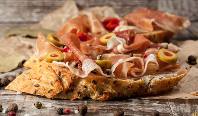 Bruschetta with roasted bell pepper, prosciutto, garlic, olives, spices and herbs. Appetizers.