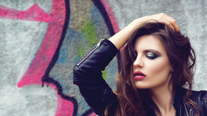 Fototapeta premium Fashion sexy girl with bright makeup. Sexy pretty and successful. Street style fashion woman. Girl in leather jacket. Sensual lips. Makeup lips. Bright makeup eye. Portrait woman makeup. Red lipstick.