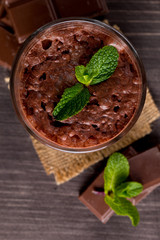 Chocolate, coffee, milk, banana shake on wooden background. Smoothie with mint. Milkshake. Protein diet. Healthy food and drink concept.